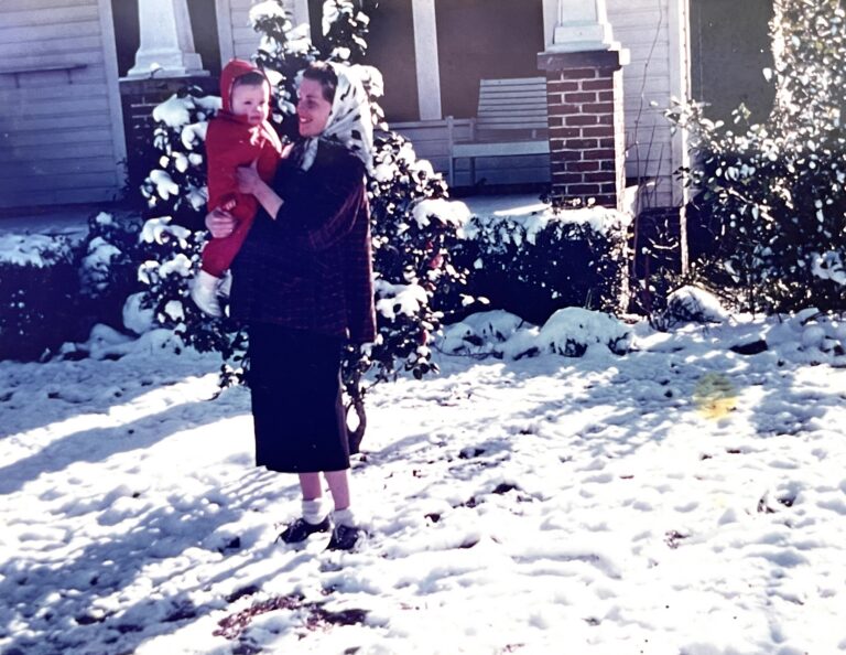 A woman holds a child in the snow in Monticello, 1958