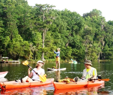 A group of paddlers in kayaks and on a paddleboard