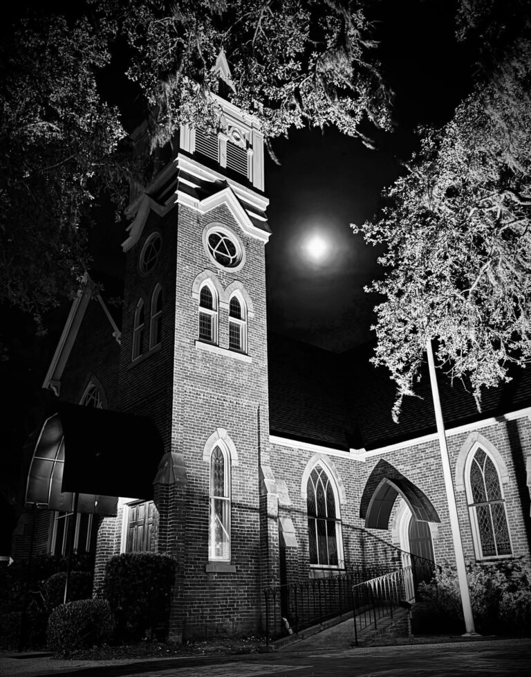 Church bell tower under a full moon, black and white photo