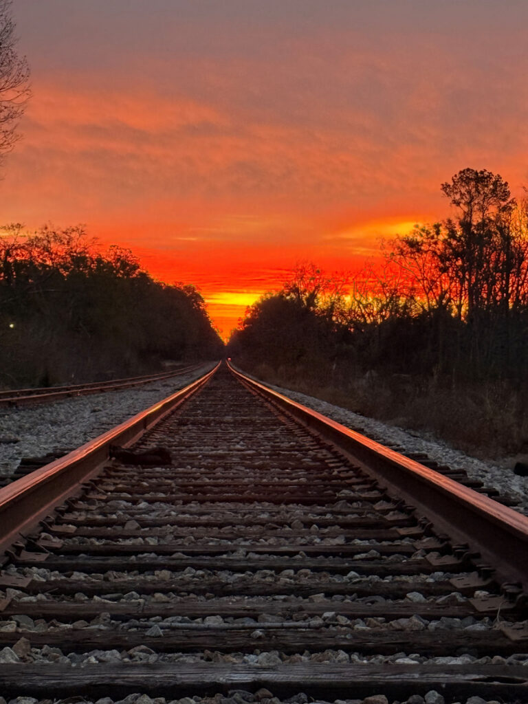 Railroad tracks on Salt Road stretching toward a red and orange sunset